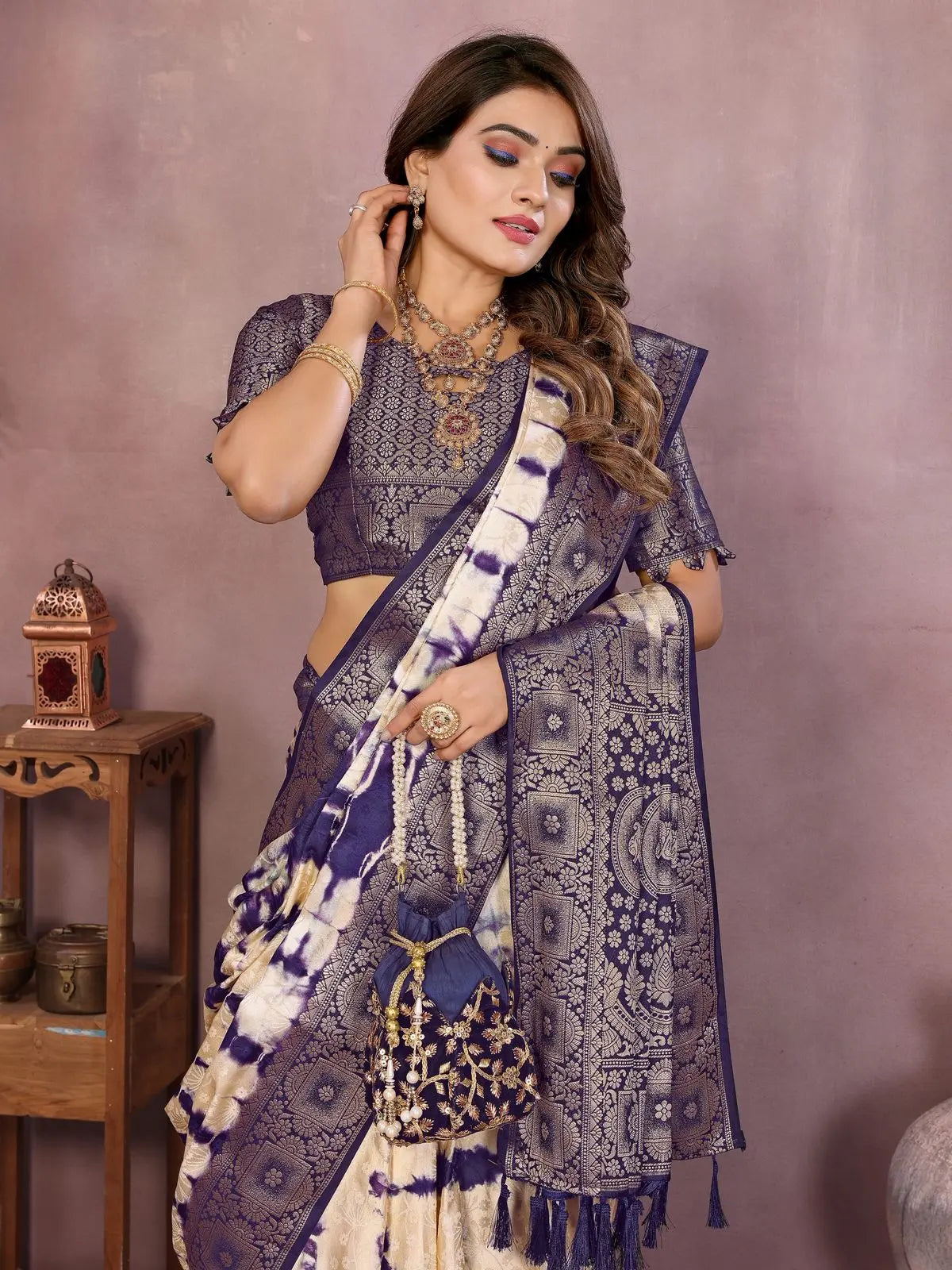 Woman wearing a traditional saree with intricate patterns against a plain background